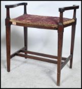 An Edwardian mahogany piano stool having upholstered seat with hinged top flanked by scrolled