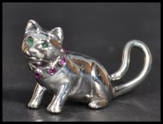 A sterling silver figurine of a cat having an inset ruby collar with emerald eyes. Weighs 12 grams.