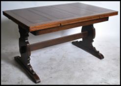 A 1930's oak Jacobean revival oak draw leaf refectory dining table being raised on lyre shaped