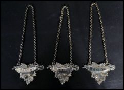 A group of three vintage 20th century silver white metal decanter labels. The labels of leaf form on