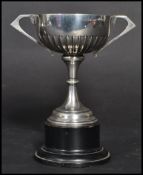 An early 20th century Art Deco silver hallmarked trophy cup raised on an ebonised wooden plinth