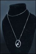 A 9ct white gold diamond pendant necklace having a circular wave pendant with diamond to centre. Set