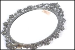 An early 20th century oval wall mirror having a silver plated scrolled and acanthus leaf frame. 34cm