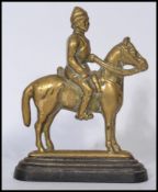 A 19th century Boer War brass doorstop in the form of a cavalry man on horse raised on a terraced