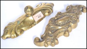 Two 19th century Victorian brass doorstops of scrolled form and the other having a finial to top