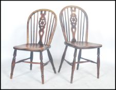 A pair of 19th century English Windsor antique elm star back and spindle dining chairs raised on