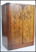 An early 20th century Art Deco walnut linen press tallboy cupboard having an inset plinth  base with