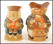 Two Doulton Lambeth Toby jugs. One seated on an X X barrel and the other riased on a domed base.