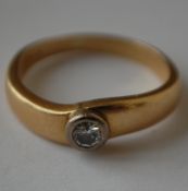 A hallmarked 18ct gold and diamond solitaire ring having a bezel set round cut diamond. Diamond