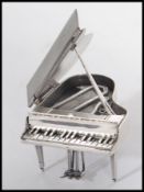 A sterling silver miniature grand piano raised on