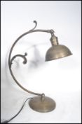 A 20th century art deco style brushed metal desk lamp having a curved arm with scroll work