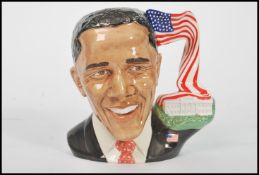 A Royal Doulton character jug depicting President Obama D7300, handle modelled as the white house