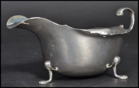 An early 20th century silver hallmarked Edwardian sauce boat having a shaped scroll handle raised on