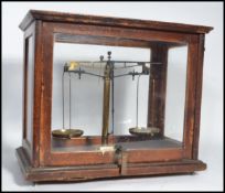 A cased set of early 20th century scientific scales with glass oak case having inset scales.