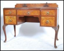 An early 20th century walnut Queen Anne revival writing desk having a series of drawers with central