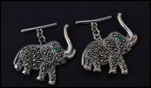 A pair of sterling silver and marcasite cuff links in the form of elephants having emerald set eyes.