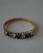 A hallmarked 9ct  seven stone gold ring being set with alternating white and purple stones.