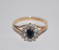A hallmarked 9ct gold cluster ring  having a central oval cut blue sapphire surrounded by a CZ halo.