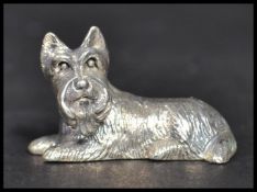 A sterling silver cast figurine of a dog in a seated position. Weighs 13 grams.