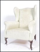 An Edwardian mahogany wing back armchair being raised on cabriole legs with castors having a good
