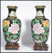 A pair of 20th century Chinese Cloisonne vases having black grounds raised on socle plinth bases.