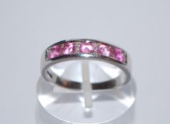 A hallmarked 9ct white gold ring having 5 channel set pink stones (tests indicate sapphire)