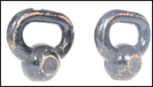 A vintage cast iron pair of kettlebells having a black painted finish.  Measures 19 cm high.