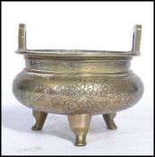 An early 20th century Chinese brass censer ding prayer bowl raised on tripod legs decorated for