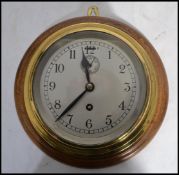 A 20th century vintage industrial brass cased ships barrel clock backed onto a circular wooden mount