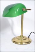 A vintage 20th century brass bankers lamp raised on a gilt circular base with adjustable green glass
