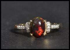 A hallmarked 9ct gold ring having a central opalescent stone with white stone shoulders. Weighs 2.