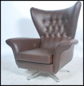 A retro mid 20th century batwing swivel armchair / chair. In the manner of G-Plan being raised on