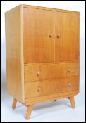 A retro 20th century limed oak tall boy, two cupboard doors opening to reveal shelved interior above