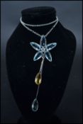 A white gold flower pendant necklace set with aquamarine and citrine stones. On silver chain