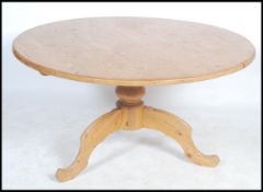 A 20th century country large pine dining table of circular form raised on a single pedestal base