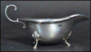 A silver hallmarked early 20th century sauce gravy boat having a shaped scroll handle raised on