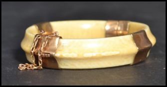 An early 20th century 9ct gold  mounted hinged ivory bangle