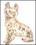 An early 20th century cold painted bronze figurine of a dog modelled in a seated position.