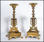 A pair of 19th century Victorian cast brass candlesticks raised on square gallery bases on four ball