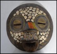 An unusual carved wooden and brass with shell inlaid wall mask. Inset with brass triangles and