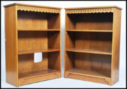 A pair of 20th century matching oak open bookcases each with a series of adjustable shelves raised