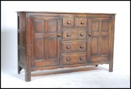 A mid 20th century Ercol beech and elm sideboard having an central bank of five / 5 drawers