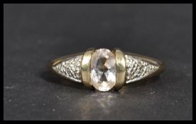 A hallmarked 9 carat gold ring with an oval clear stone in the centre with diamond chip illusion set