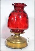 A vintage 19th century brass and cranberry glass oil lamp by Superba. The large flat brass reservoir