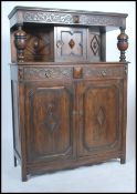 An Elizabeth style oak court cupboard, with a carved frieze top over a single door cupboard and