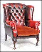 An antique style oxblood button back leather chesterfield armchair having barrel arms, raised on