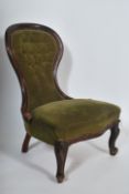 A Victorian mahogany spoon back nursing chair raised on cabriole legs with hoof feet having green