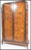 A 1930's Art Deco walnut double wardrobe being raised on cabriole legs with pad feet having twin