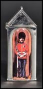 A sterling silver vesta case in the form of a sentry box having an enamel guardsman. Weighs 37