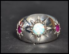 A sterling silver opal and ruby dress ring. The three stone ring being star set. Size S weighs 9